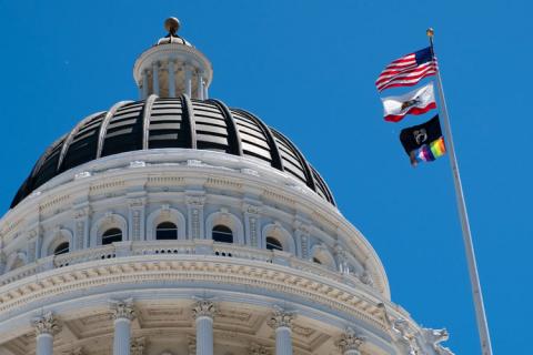 California State Capitol with flag pole containing American flag, California State flag, National League of Families POW/MIA flag, Progress LGBTQ Pride flag